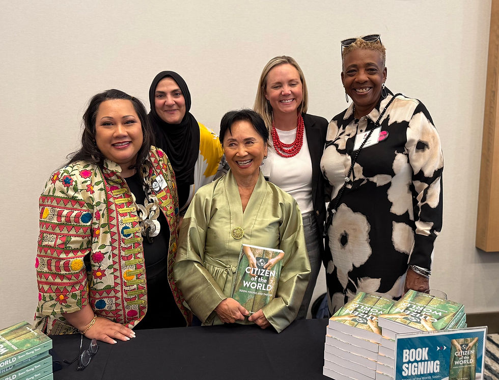Five women smile at the camera, holding a book, book signing event. Soon-Young Yoon