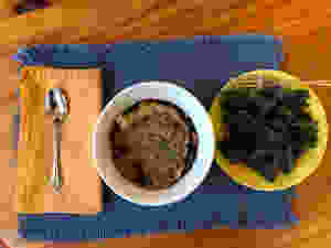 Whole foods, plant-based breakfast of steel cut oats, banana, blueberries, cinnamon, flax seeds, chia seeds, and green matcha powder.