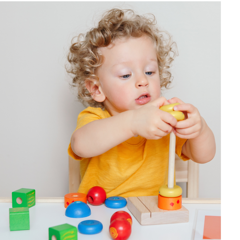 a young boy with curly hair placing a large yellow bead on a wooden spindle that has an orange and yellow bead already on it.