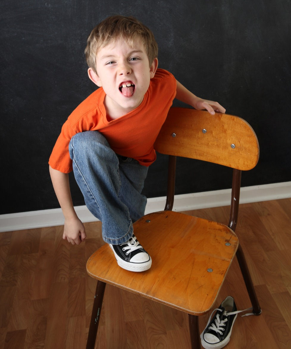 boy standing on chair sticking out his tongue