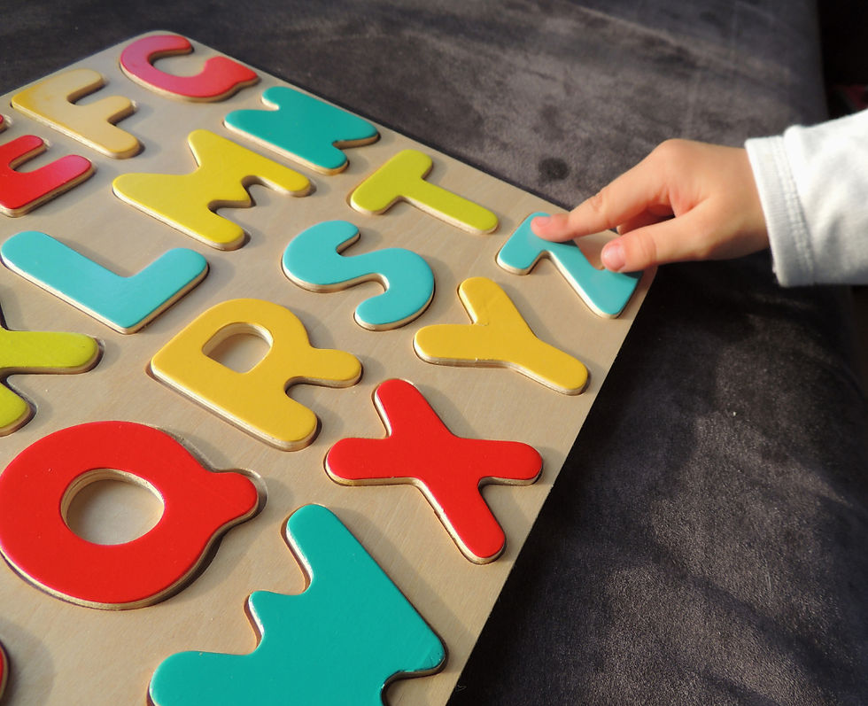 a hand of a small child placing letter in an alphabet puzzle.