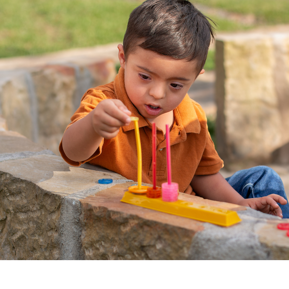 a boy in an orange shirt placing a yellow bead on a yellow spindle next to a red and pink spindle with matching-colored beads on them.spindle