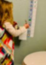 Child in colorful dress uses visual potty training schedule for autistic child. Checklist includes images with checks.