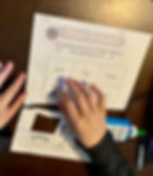 child completing worksheet. shows just hand placing cut out picture of a dog to the word dog.