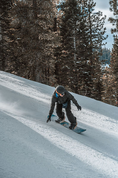 Snowboard skidding a toe side turn down a crusted and dusted trail