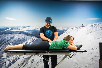 A women gets help to fix her back pain with soft tissue massage in front of a large image of Mount Mansfield