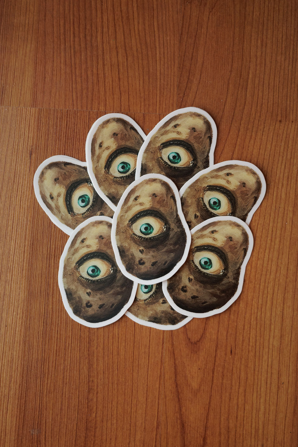 Thumbnail: many stickers, of a russet potato with a teal eye, piled together