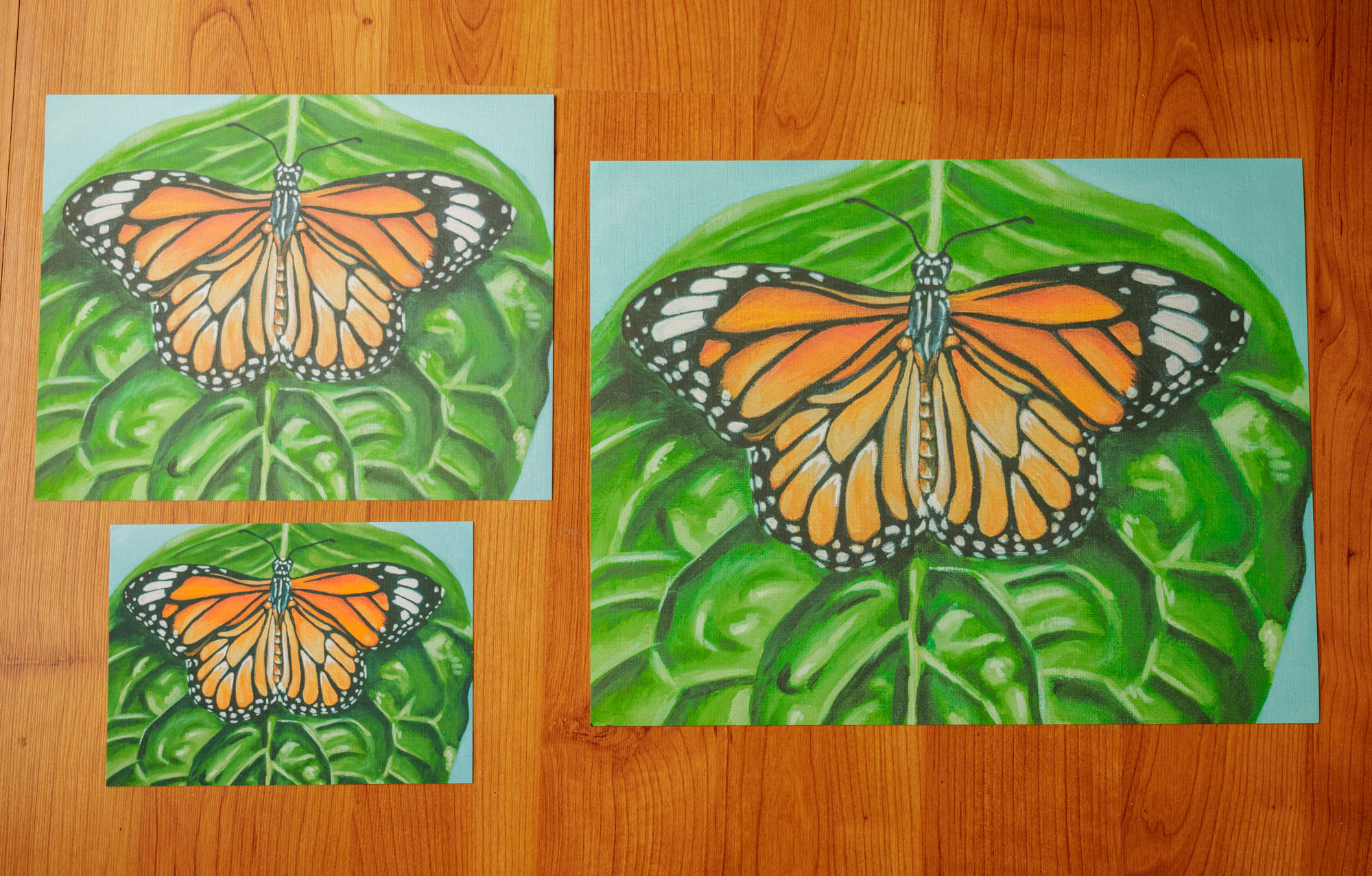 three sizes of prints of an orange monarch butterfly on a green leaf