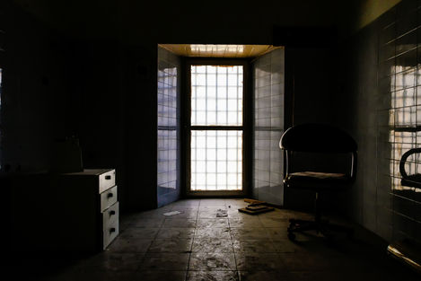 a dark room with a window and a chair