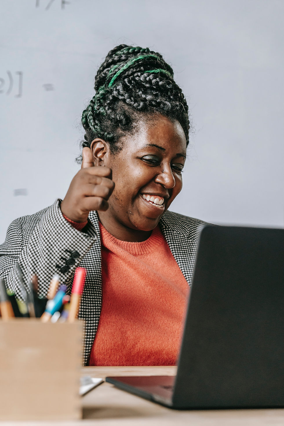 Woman giving thumbs up while looking at computer screen