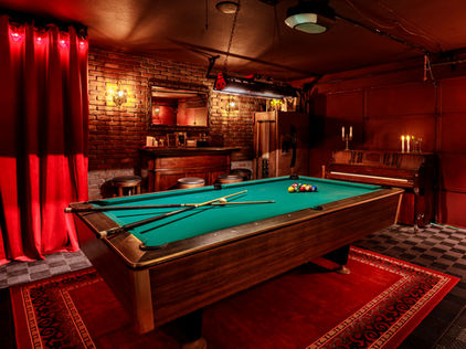 Speakeasy with red drapes, red rug, billiard table 