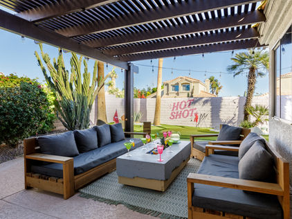 Image showing outdoor seating, colorful drinks on the table, minigolf in the background and mural on the fence saying “HOT SHOT” in pink color