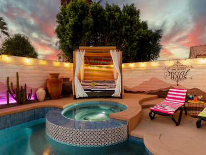 Image showing a jacuzzi and pool with cabana and lounger chairs with mural on the fence that says “The Secret Social Haus”