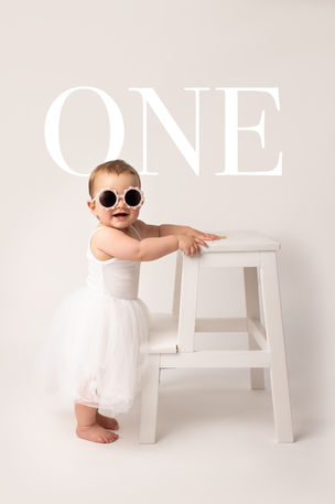 Baby's first birthday portrait wearing stylish sunglasses smiling happily at the camera