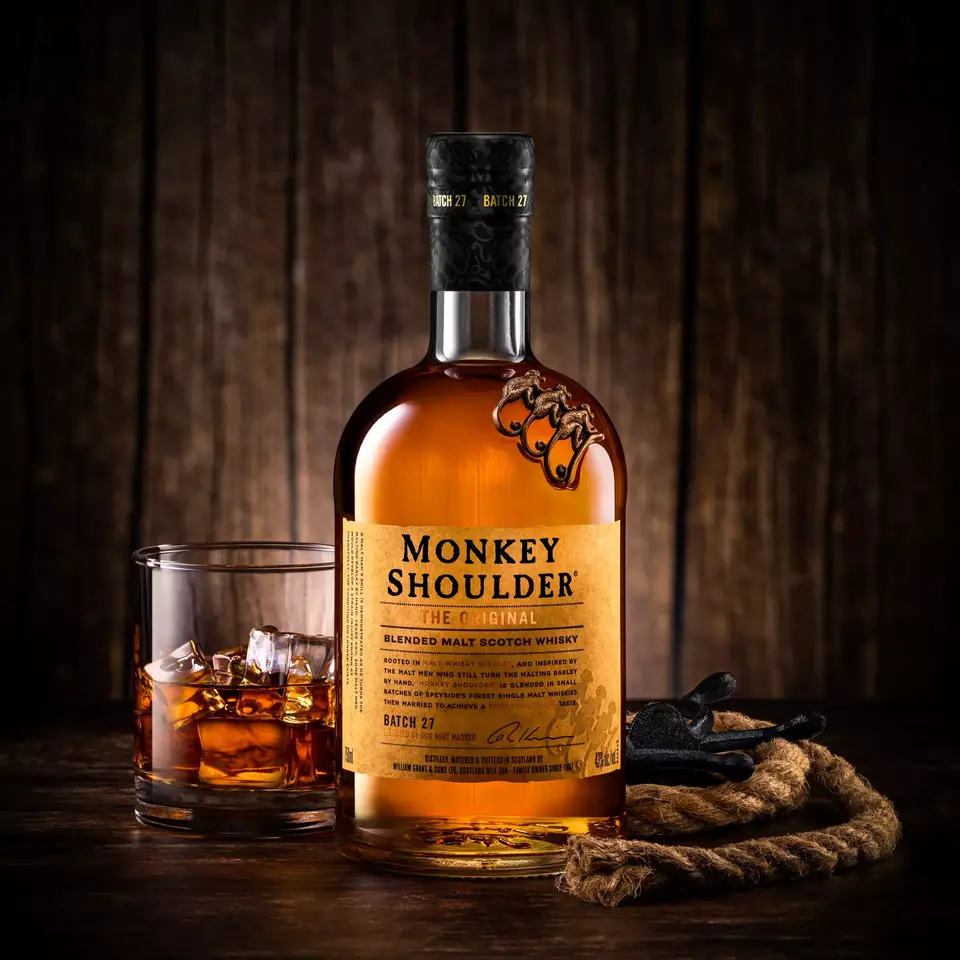 Rustic lifestyle product shot of Monkey Shoulder Whisky with a rope, leather gloves, and a glass