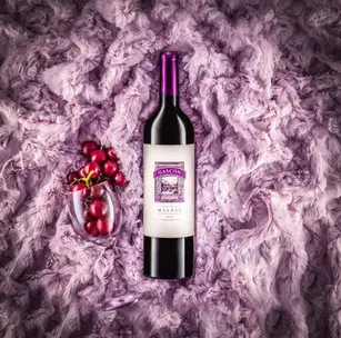 Luxury wine photography with a bottle centered on a soft purple textured fur background