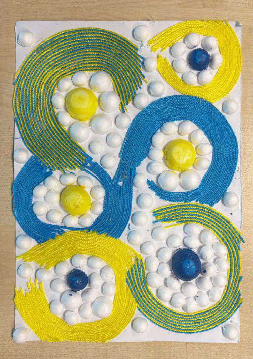 Materials: Blue and yellow colours, round styrofoam, gouache paint, waxed thread, and
PVA glueI used vibrant colored thread and circular shapes to mimic smiles and bubbles. The
placement is intentionally random to reflect the ease and playfulness of that time. I
paired yellow and blue, which bring warmth, and when you squint, they give the illusion
of green, symbolising harmony.