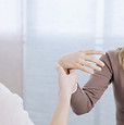 A woman gently touches the hand of another woman, conveying a moment of connection and tenderness between them.