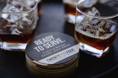 Beverages in a glass and coasters with branding on display at an event
