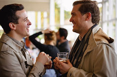 People engaging in conversation and drinking beverages at an event.