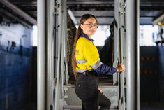 Engineer in uniform ascending stairs on a naval ship, looking toward the camera.