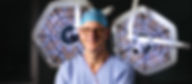 Professional portrait of a surgeon in an operating theatre, with surgical lights glowing in the background