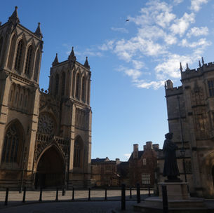 View of Bristol Cathedral and elegant buildings on College Street with a blue sky and fluffy clouds