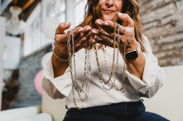 woman holding gold and silver permanent jewelry chains