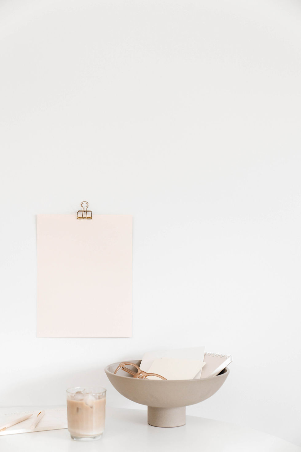 Picture of desktop with pink paper on wall in background.