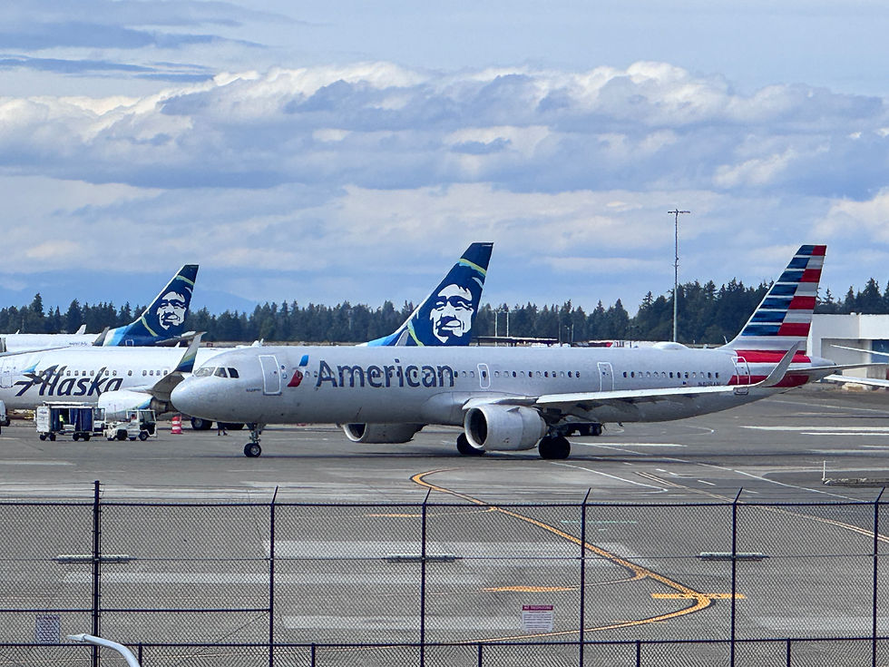 American and Alaska Airlines jets parked on a tarmac under cloudy skies.