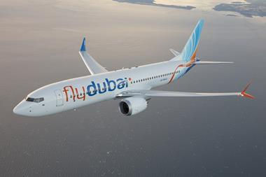Flydubai airplane in flight over the sea, showing "flydubai" logo on its side. Blue and orange tail. Calm, clear sky backdrop.