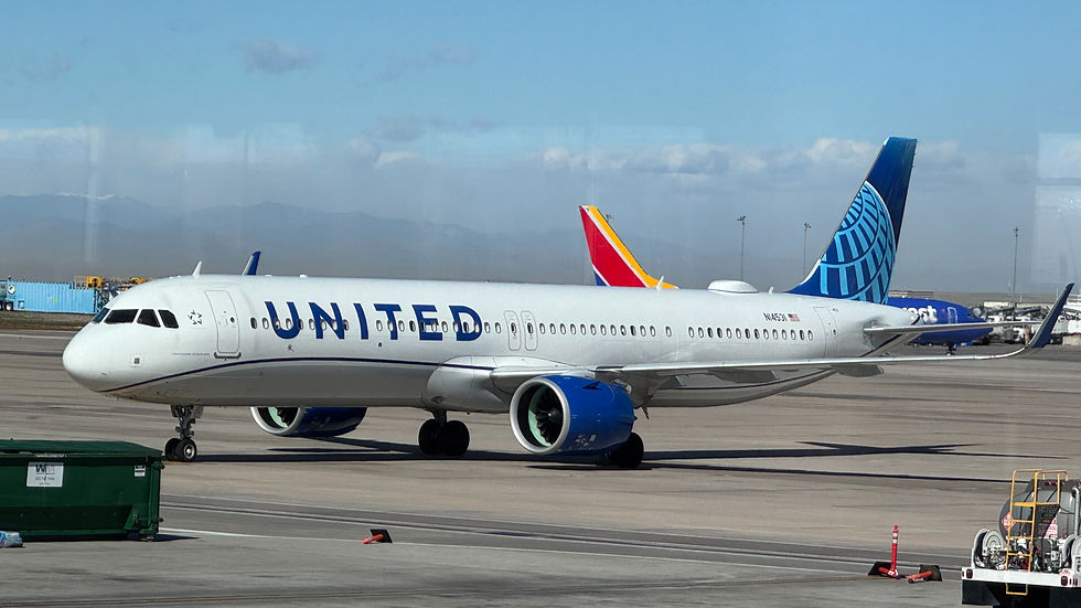 United Airlines jet taxiing on airport tarmac under blue sky, with mountains in background and UNITED on fuselage.