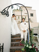 Couple standing on floral-decorated staircase at The Oviatt rooftop.