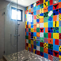 Salle de bains couleur pop chambre de service Paris 17e : douche italienne zellige multicolore, carrelage orange turquoise jaune, meuble suspendu chêne, miroir rond rétroéclairé – rénovation locatif tendance AZ DECO 2025