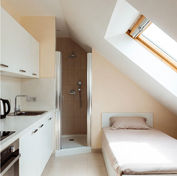 Studio combles 14 m² rénové Paris 5e Panthéon : kitchenette IKEA blanche, douche cabine sous pente, lit 140 cm coffre, carrelage beige clair, fenêtre de toit ROTHO, peinture beige doux – budget étudiant 23 200 € – AZ DECO 2025