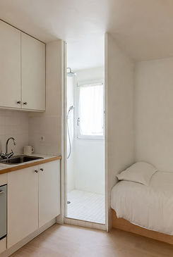 Studio 12 m² chambre de bonne rénovée Paris 12e : cuisine IKEA blanche, douche italienne ouverte, lit banquette, parquet chêne clair – budget 12 800 € TTC