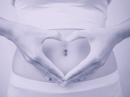 Hands in a heart shape over a belly
