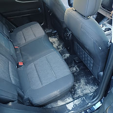 backseat of a suv that has sand on the floor
