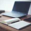 A desk with an open notebook and laptop.