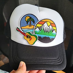 Casquette noir et blanc personnalisée avec des patches de paysages et une guitarre.