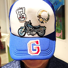Casquette bleu et blanc personnalisée avec des patches en forme de moto, une lettre et autres symboles.