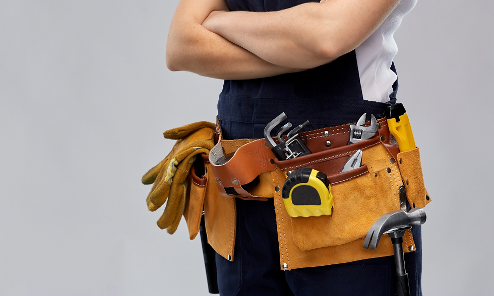 Person in a blue and white outfit, arms crossed, wearing a tool belt with gloves, pliers, tape measure, and a hammer. Gray background.