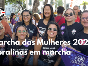 Mulheres do Movimento Coralinas participam da Marcha das Mulheres 2026 no Recife, reunidas em ato nas ruas com camisetas do coletivo e faixa do 8M.