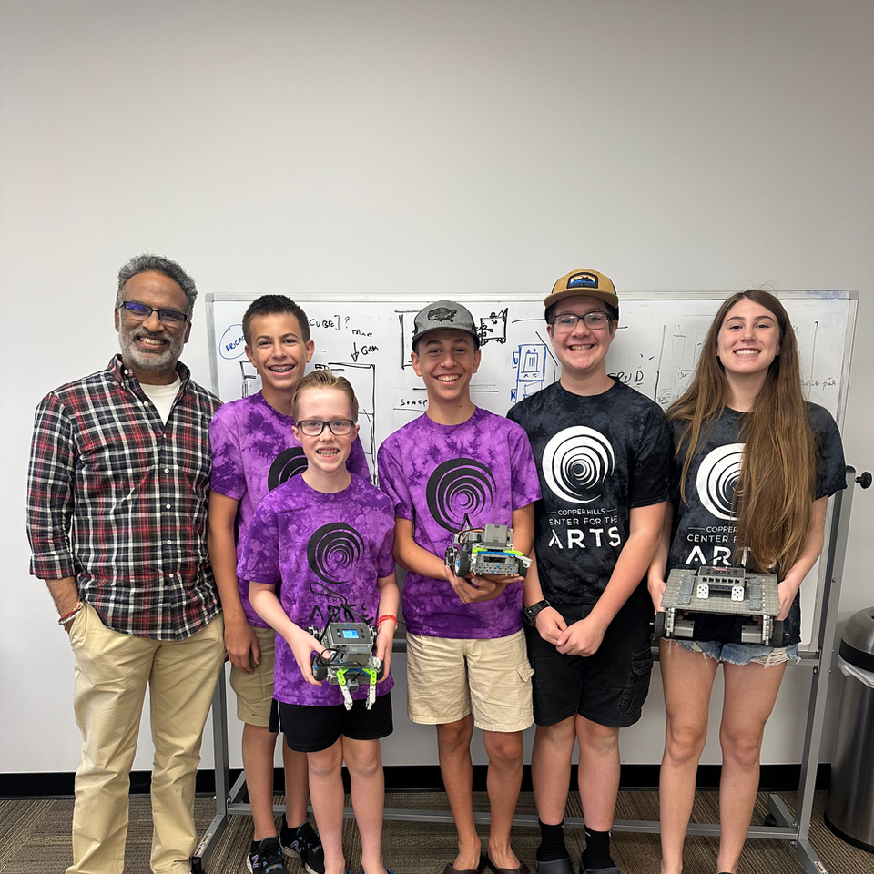 Group of students and mentor with robots in front of whiteboards ARTS