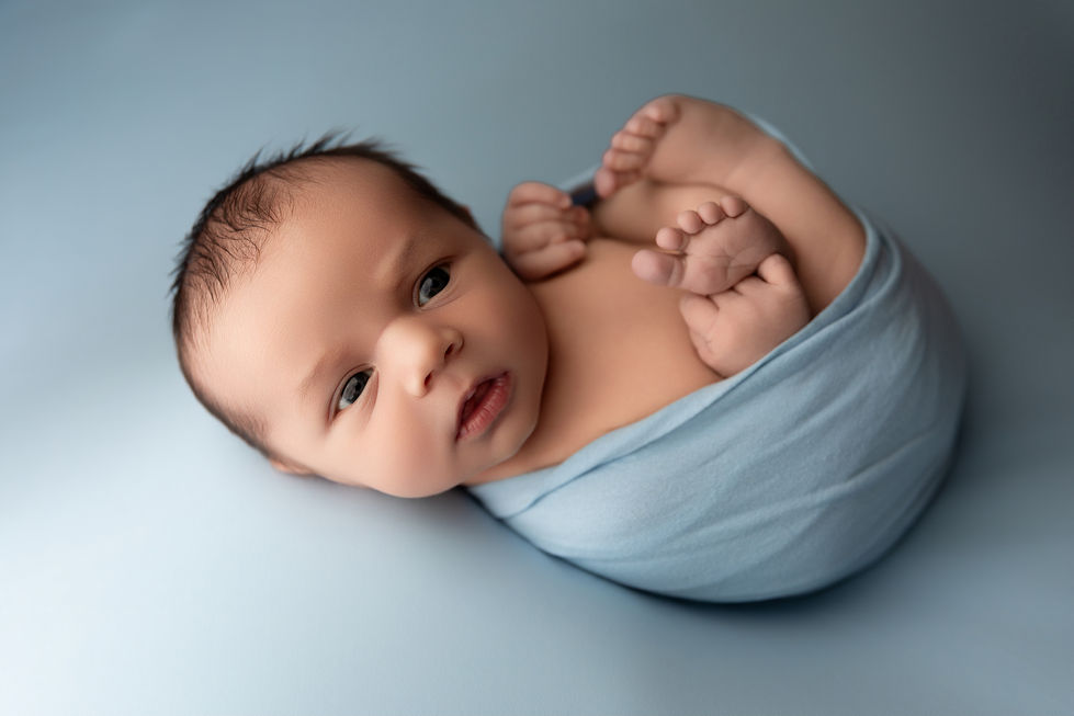 awake baby boy posed on baby blue fabric