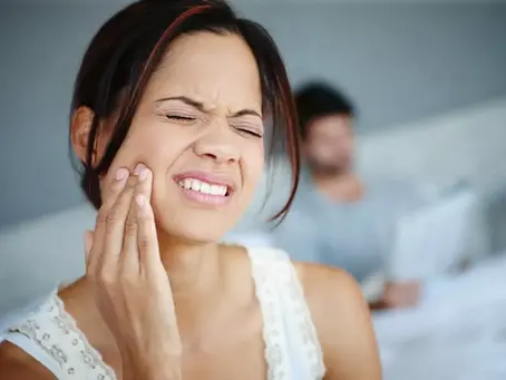 Woman gently touching her jaw, eyes closed, symbolizing the emotional connection between stress and bite alignment.