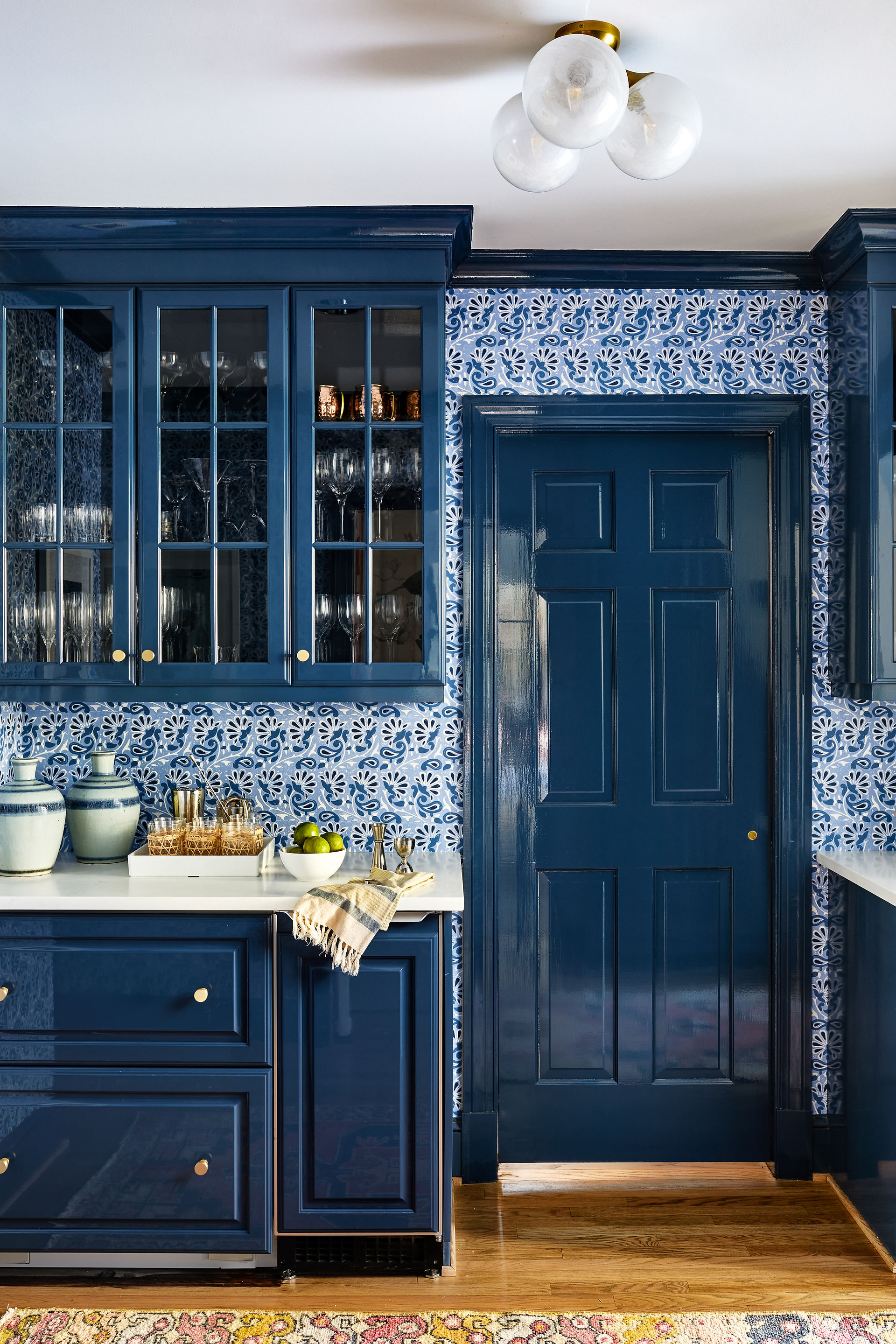 Navy blue kitchen cabinets with glass doors and daisy wallpaper 