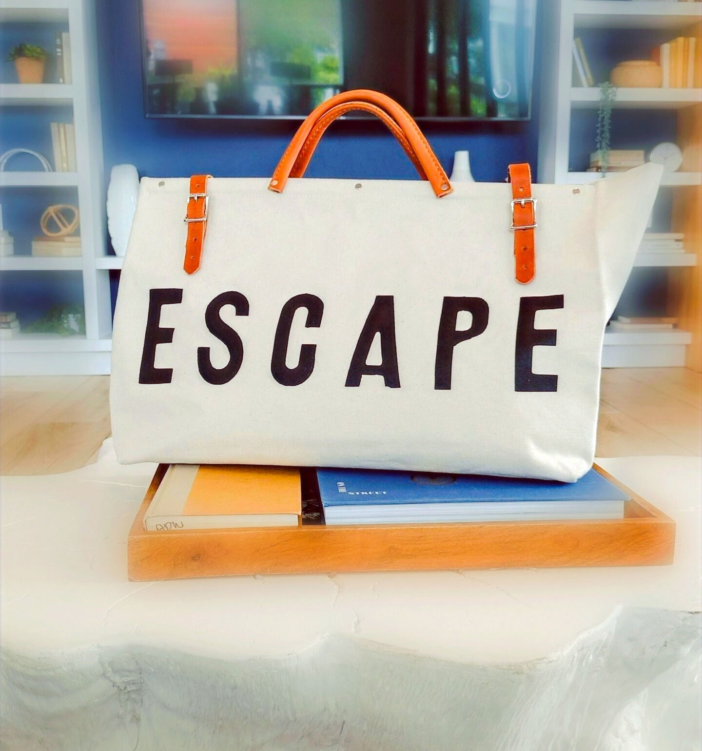 Light khaki canvas utility bag with ESCAPE on front in black capital letters. Brown leather belt straps. Forestbound