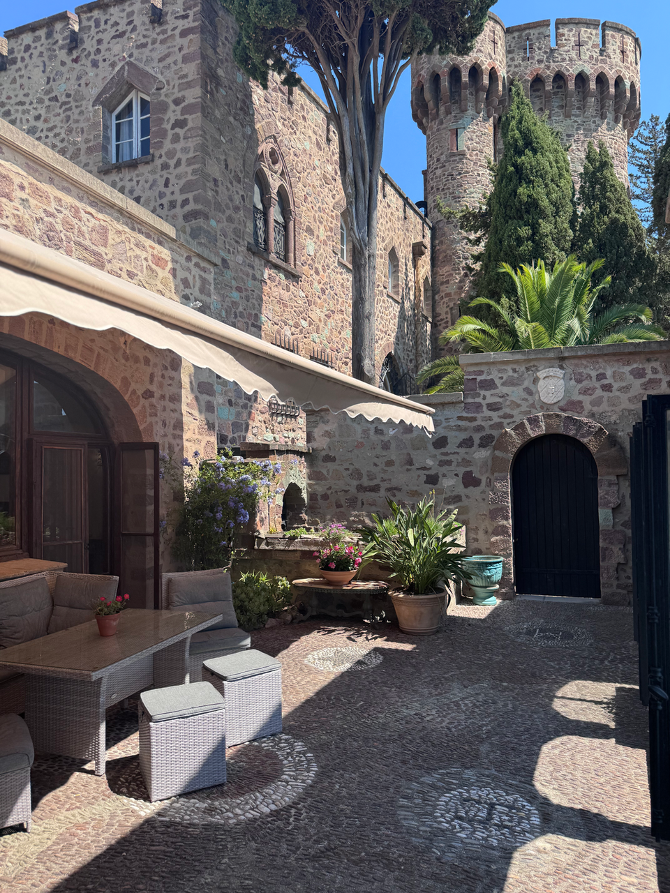 Stone courtyard patio with outdoor seating, castle background, sunny, south of France accommodations.
