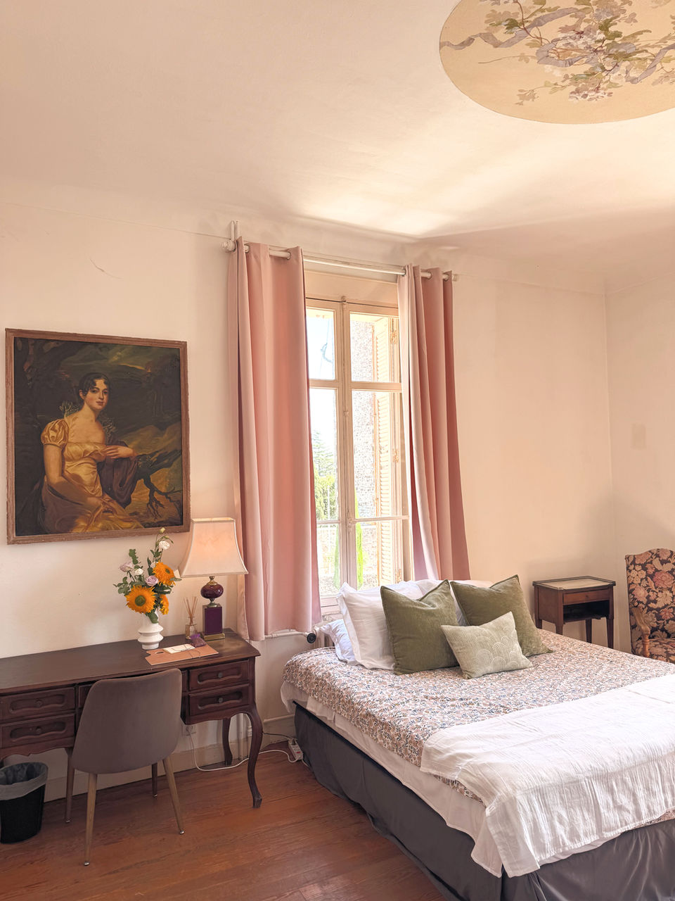 Cozy bedroom with antique desk, a painting, pink curtains, accommodations in south of France.